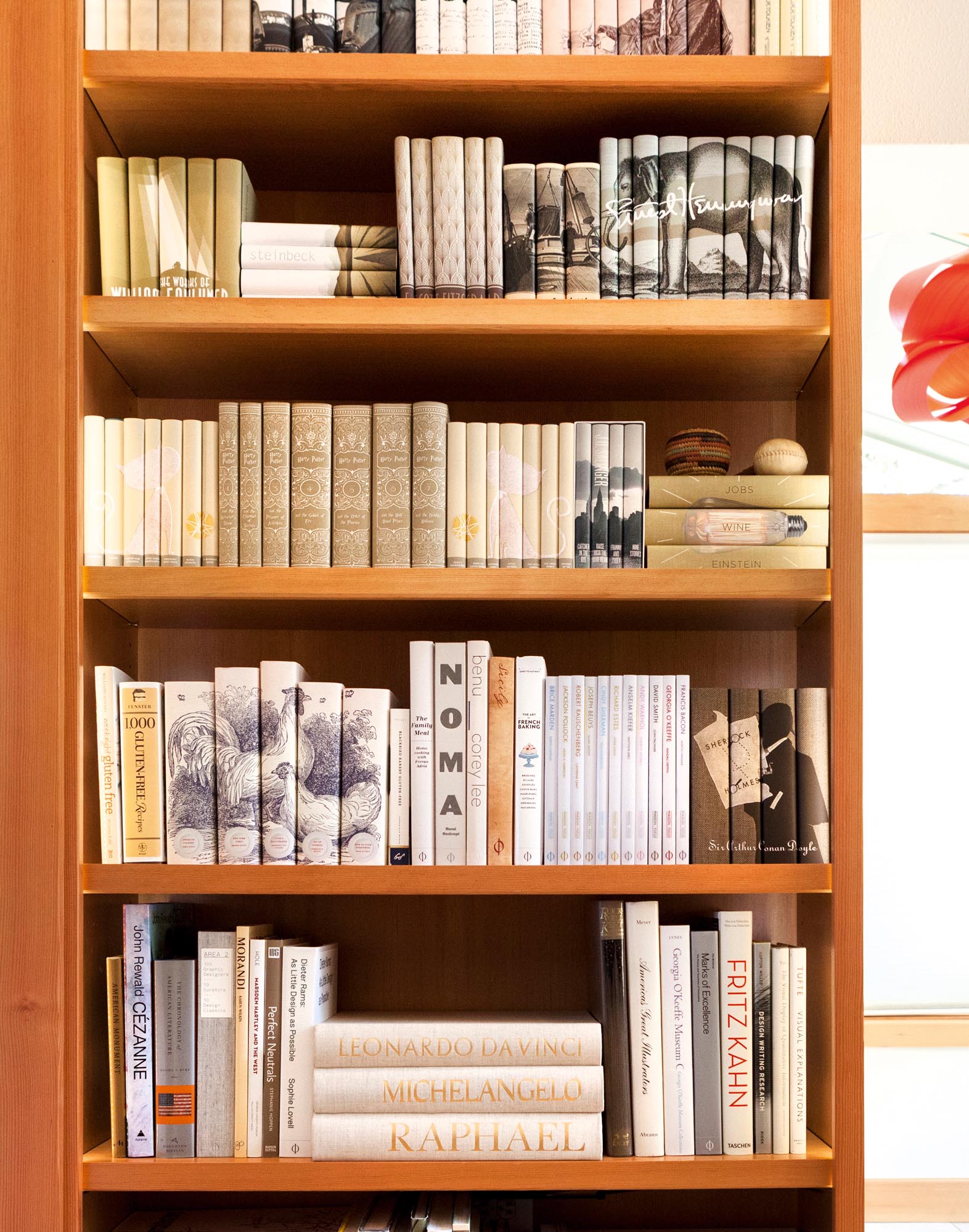 Photo of a tall bookshelf featuring books jacketed in and whites and tans.