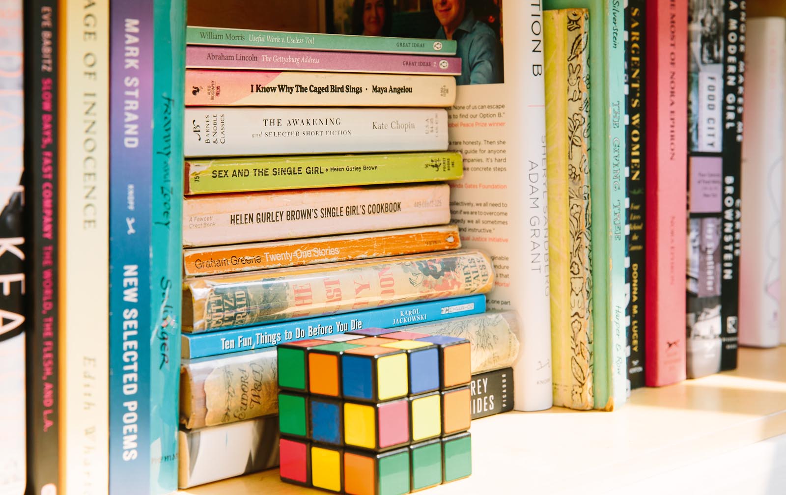 Photo of a shelf of used books with a Rubik's cube.