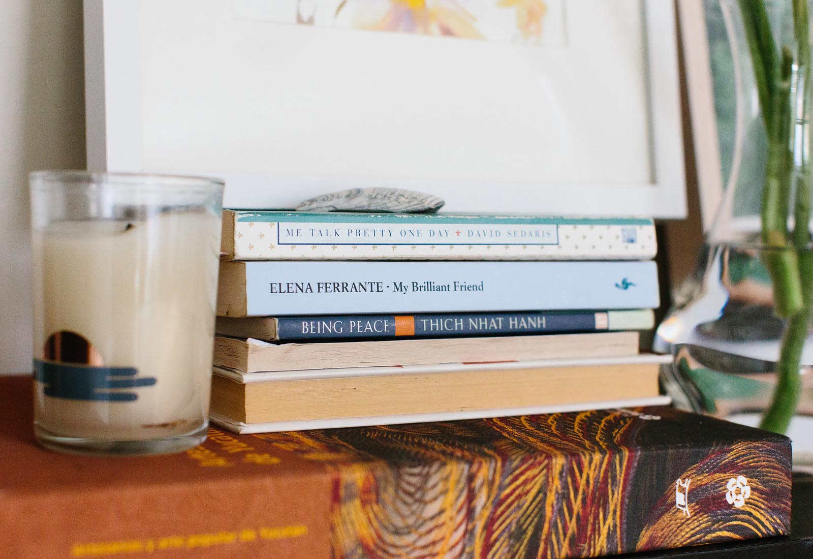 Photo of a stack of books with a candle.