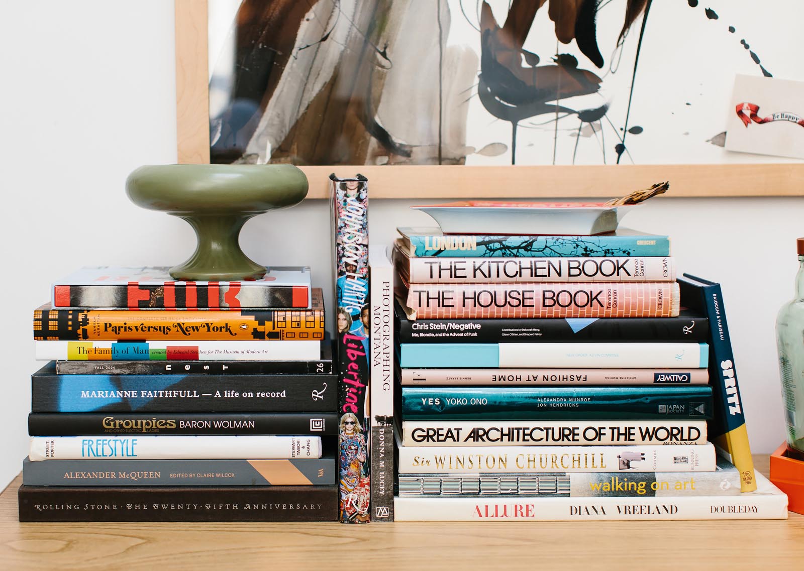 Photo of a table with two stacks of books, and more standing around them.