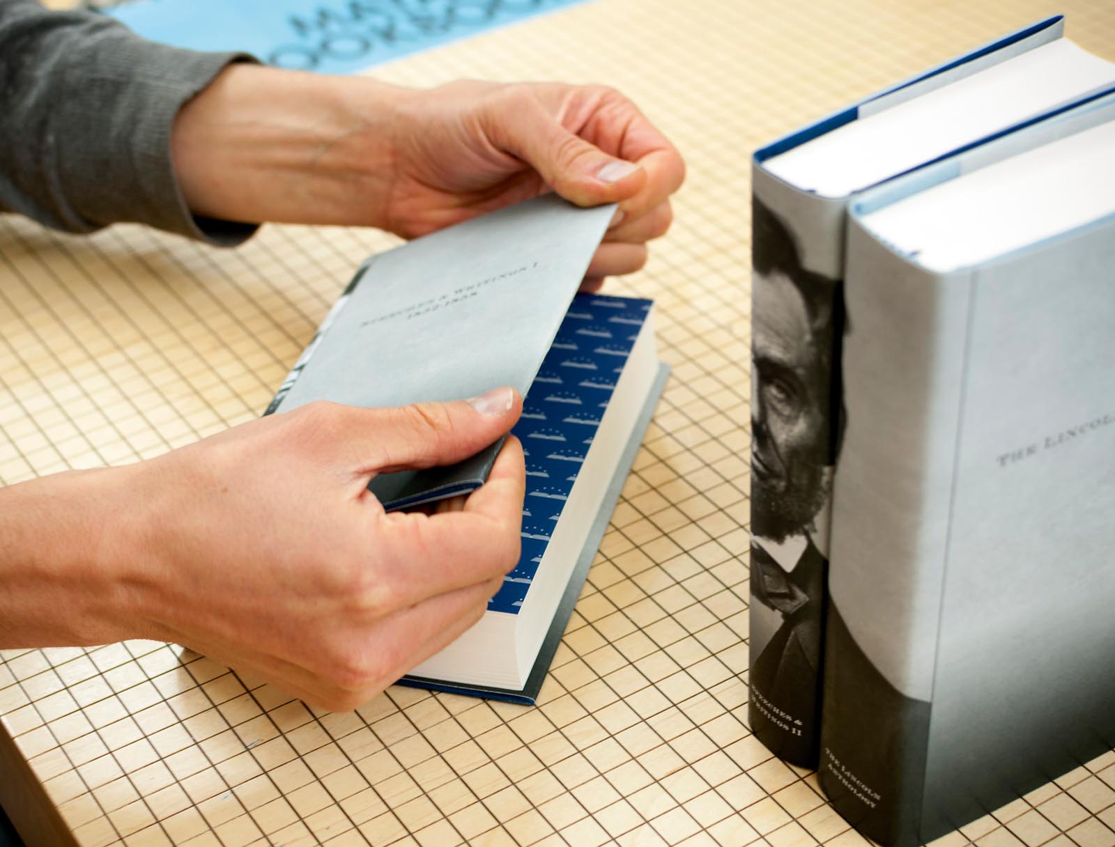 Photo of books being jacketed to form an image of Abraham Lincoln when shelved together.