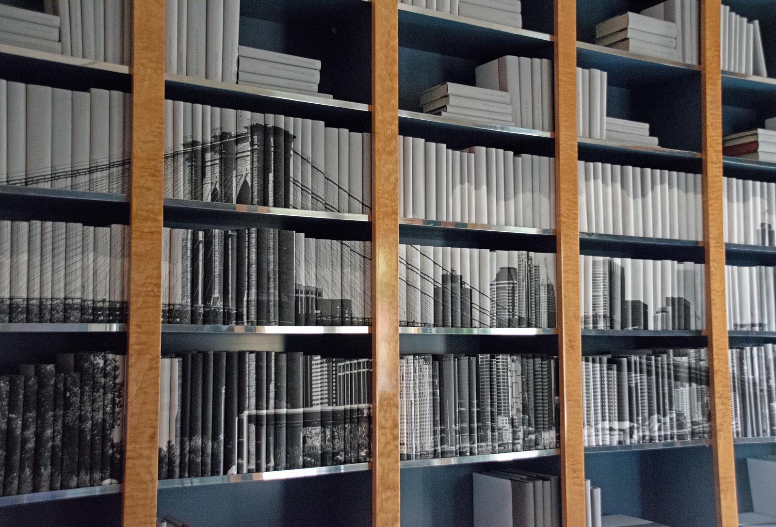 Photo of a wall of shelves with jackets in gray tones that form an image of a cityscape.