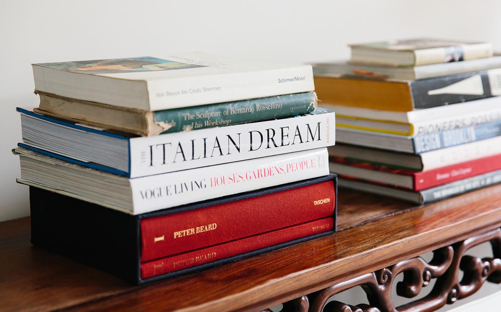 Photo of stacks of books collected on a carved wood shelf.