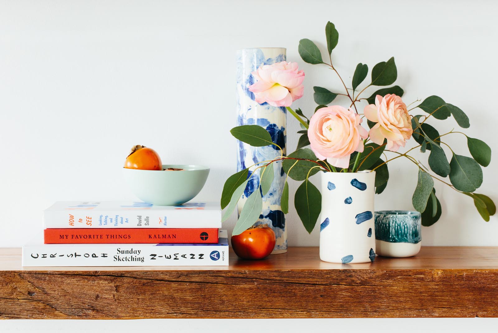 Photo of a decorative arrangement including books, a vase of flowers, candles.