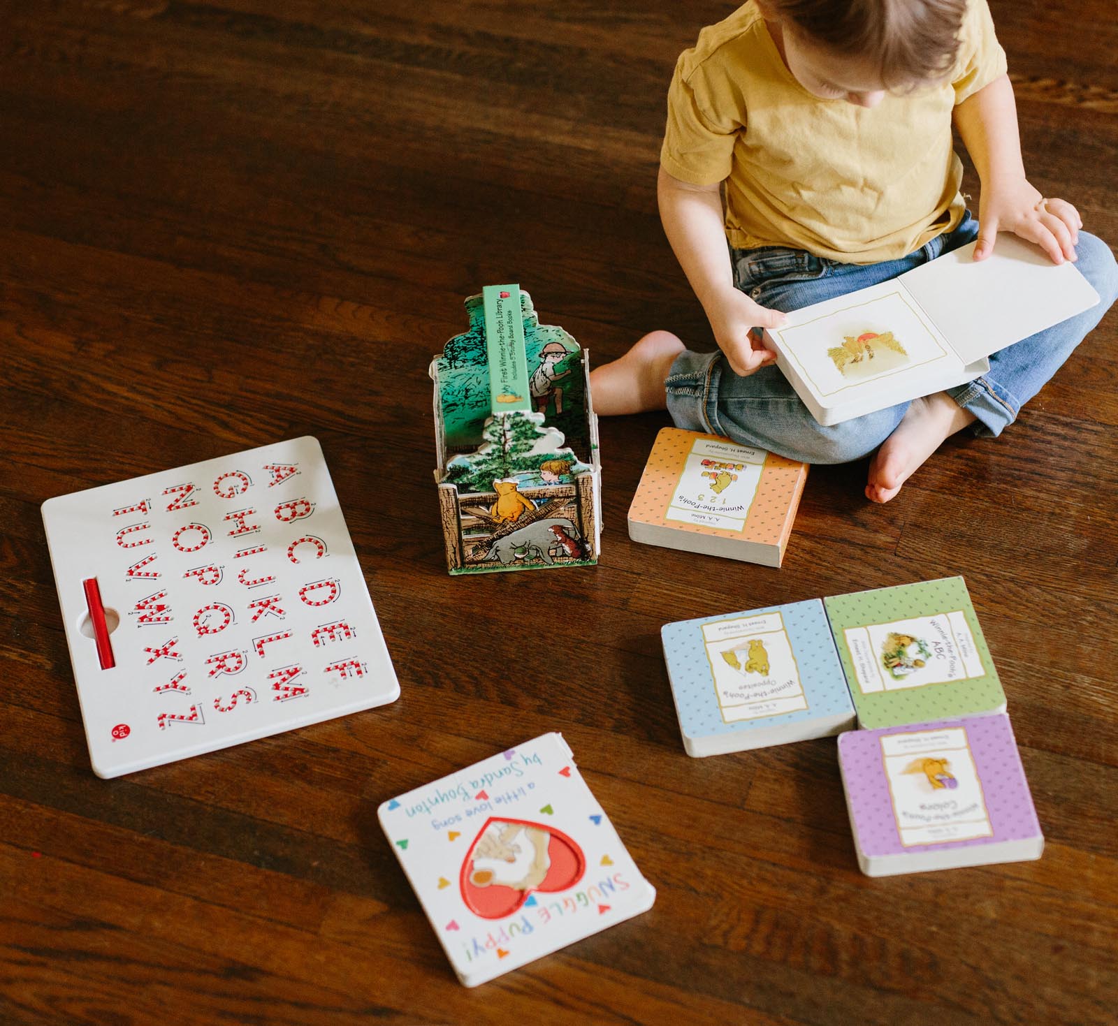 Photo of a toddler looking through board books featuring Winnie-the-Pooh.