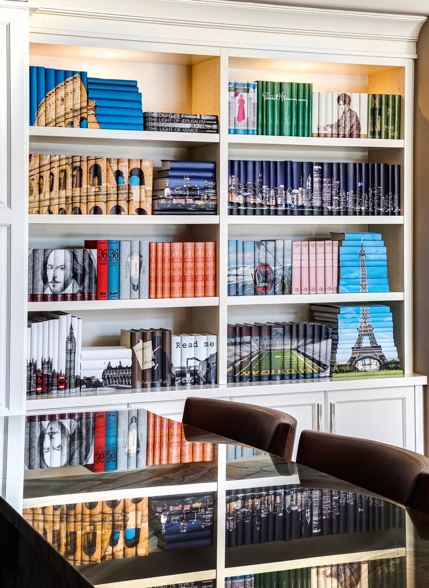 Photo of a reflective table in front of a bookcase filled with groups of images jacketed with travel destinations and author images.