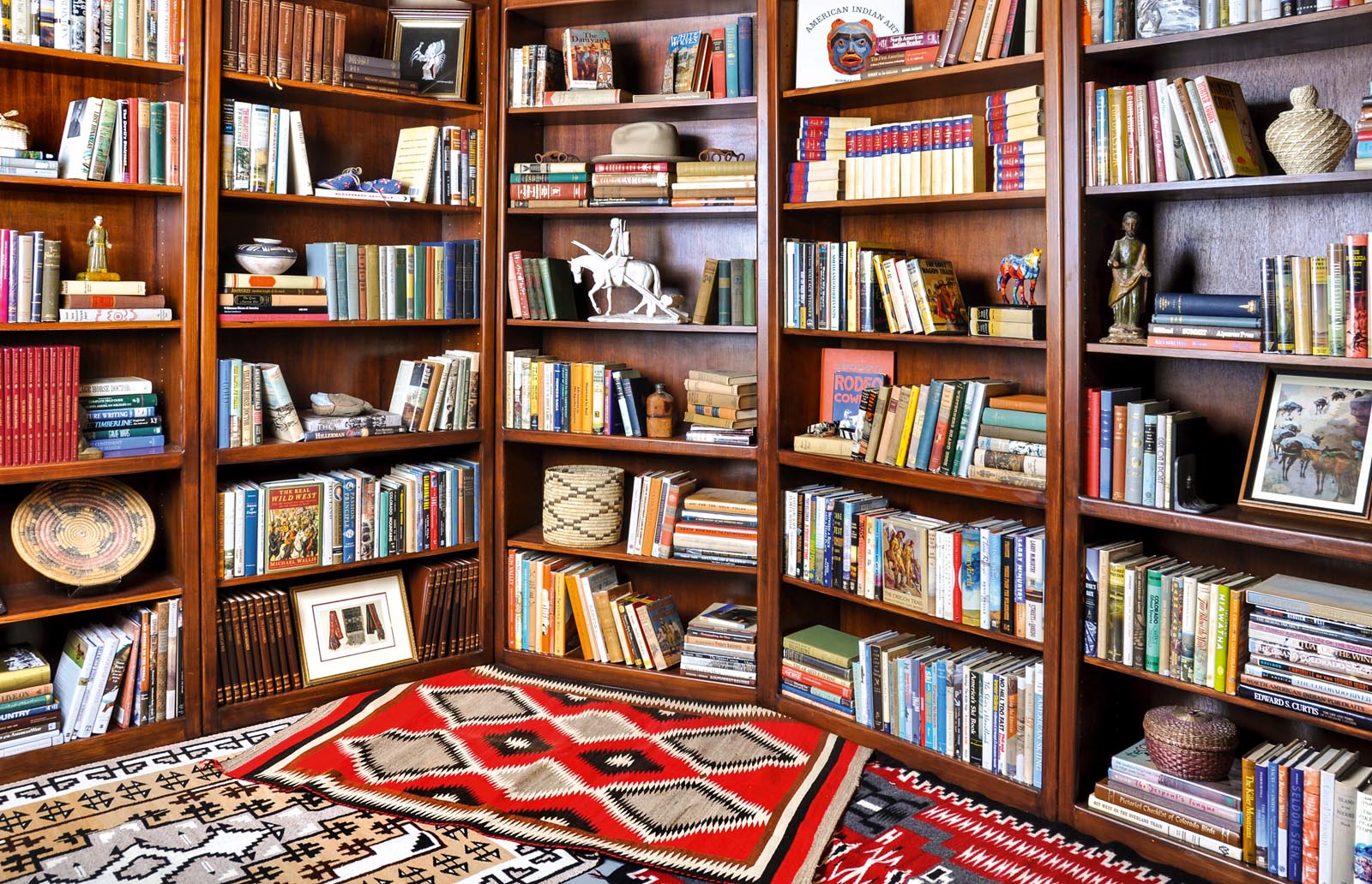 Photo of sets of shelves rounding a corner and layered rugs in front of them.