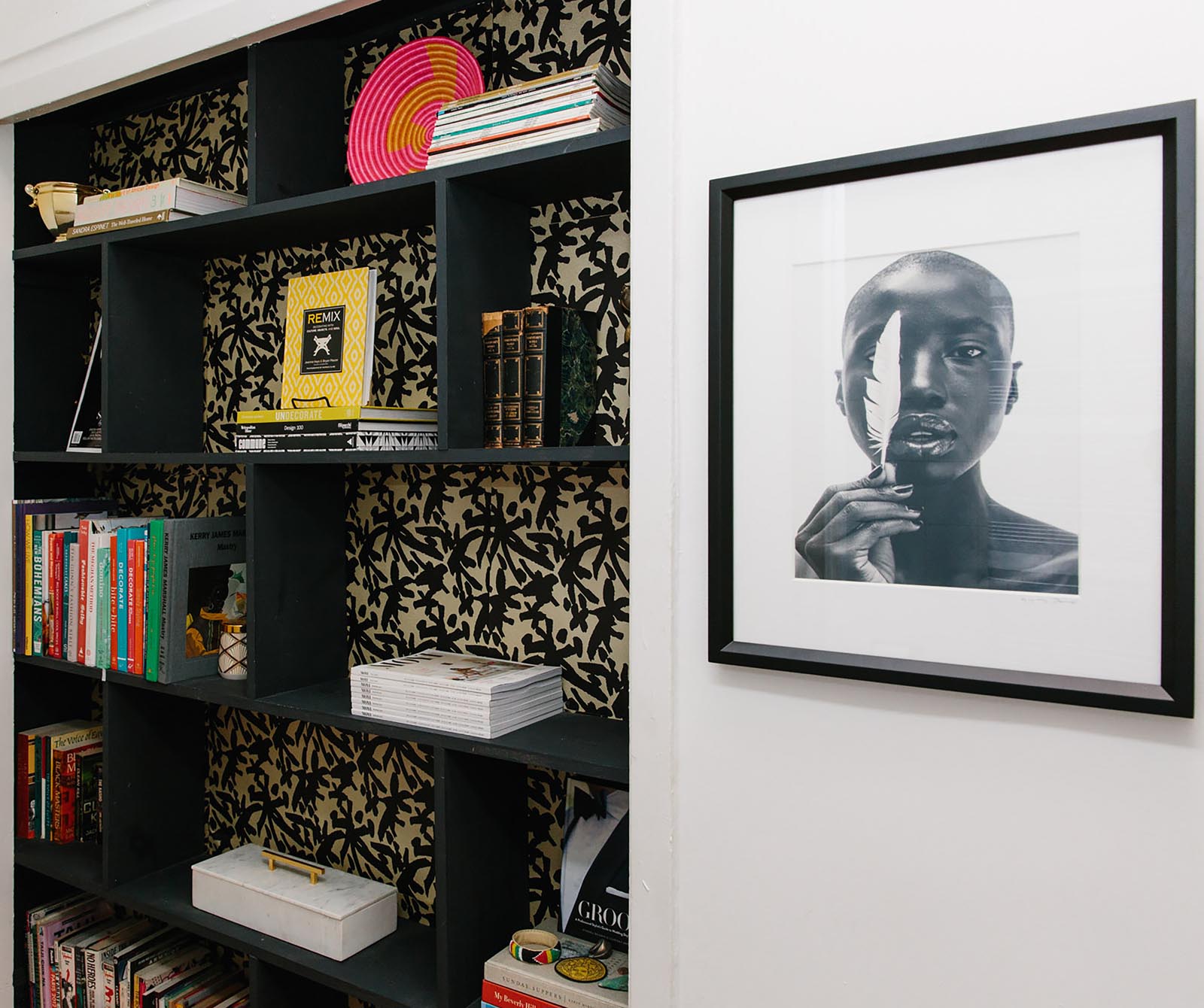 Photo of black shelves with patterned backing and stacks of books and boxes.