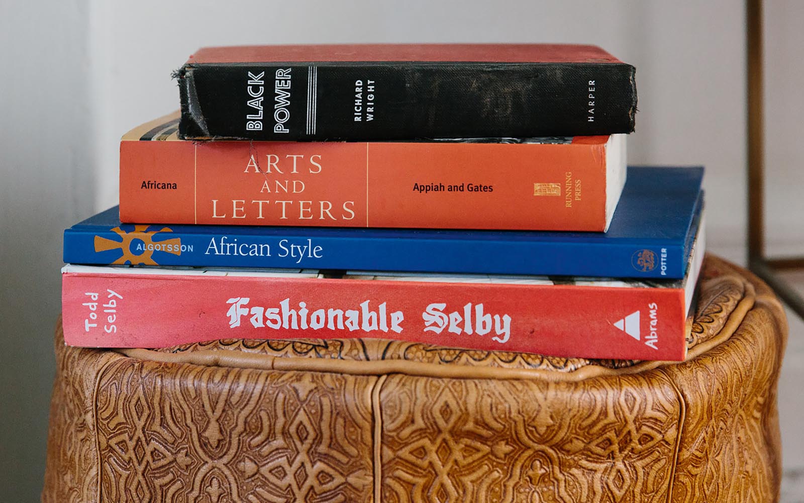 Photo of a stack of books on a leather ottoman.