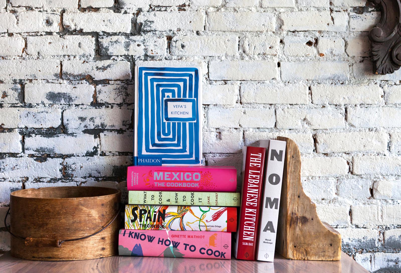 Photo of a stack of books and architectural elements grouped against a painted brick wall.