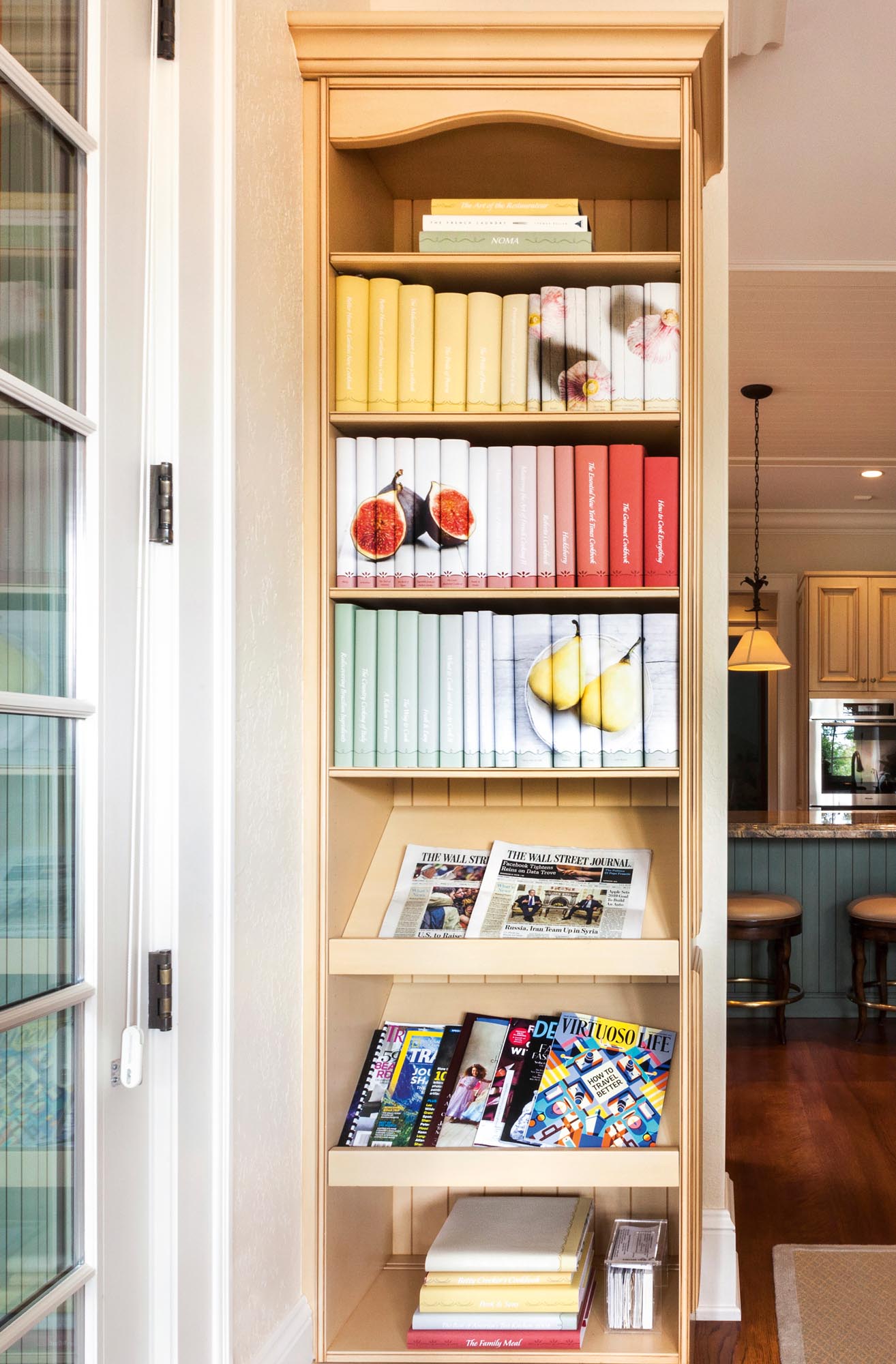 Photo of a slim, tall bookcase featuring magazines and  custom-jacketed cookbooks.