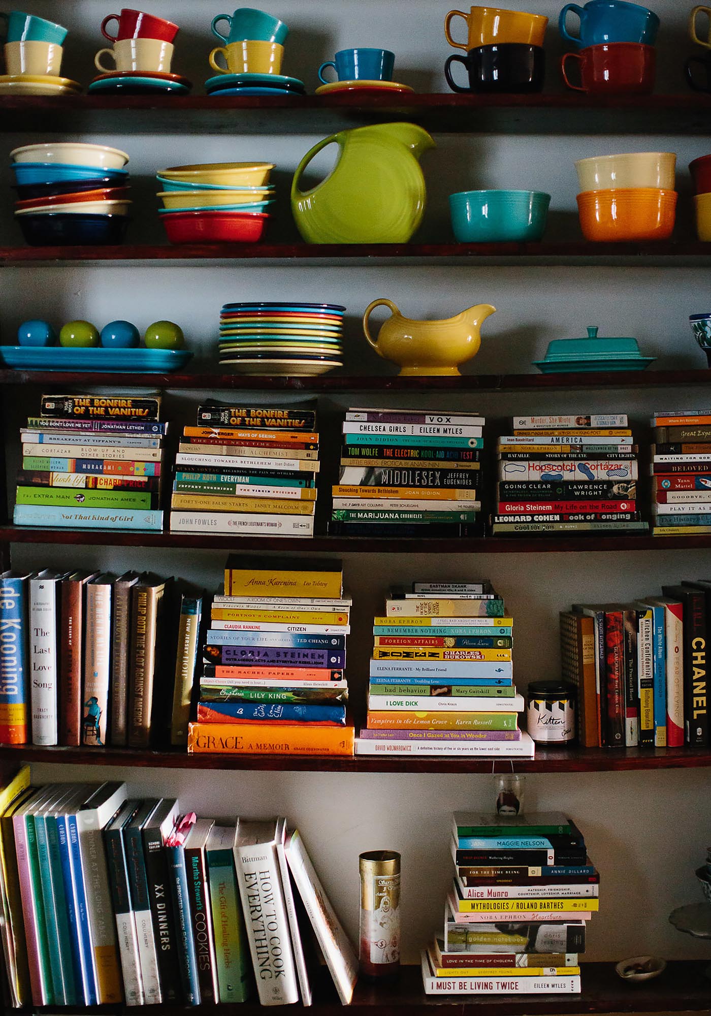 Photo of shelves filled with colorful dishes and stackes of paperbacks.