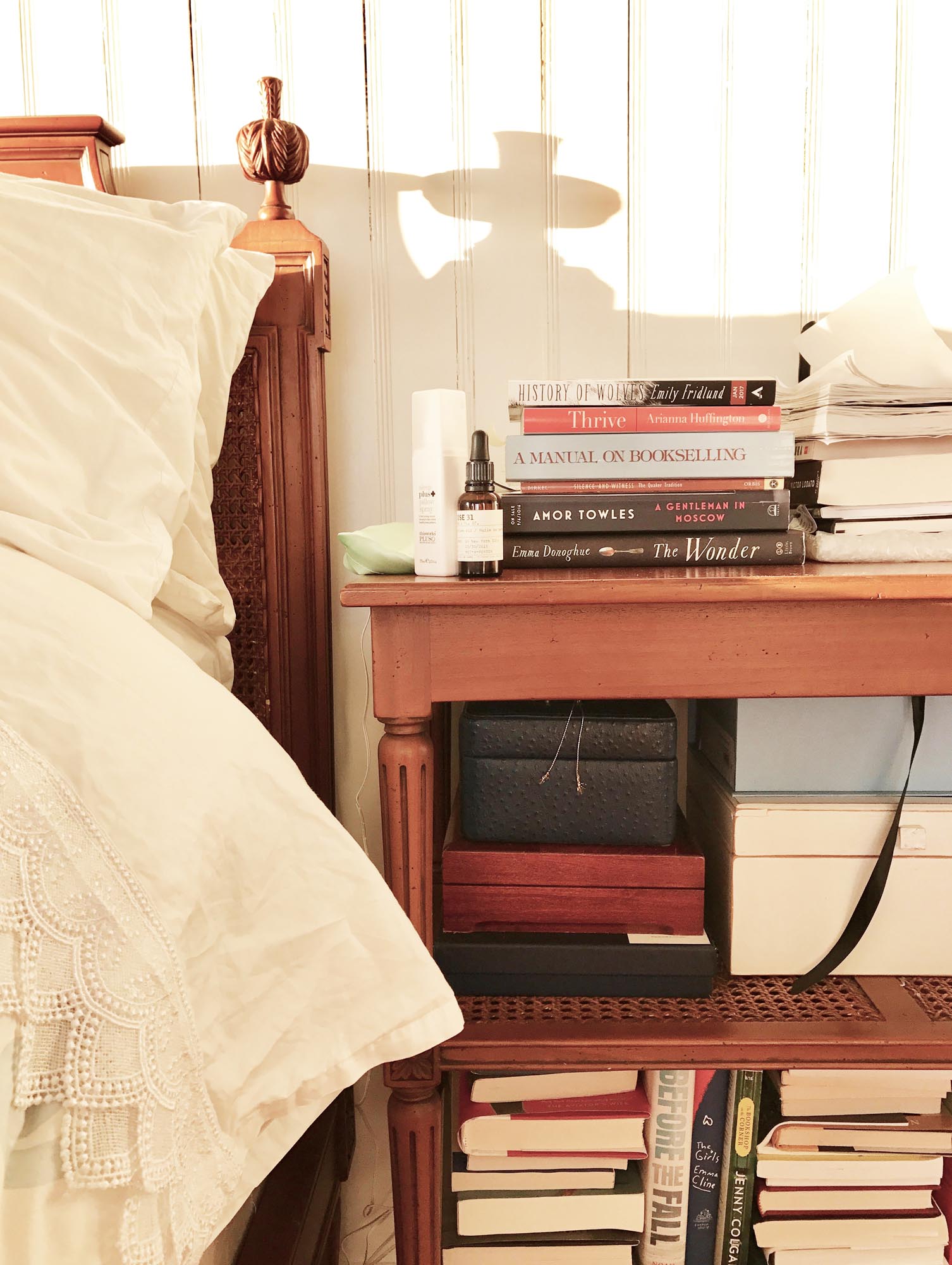 Photo of a bedside stand with stacks of books.