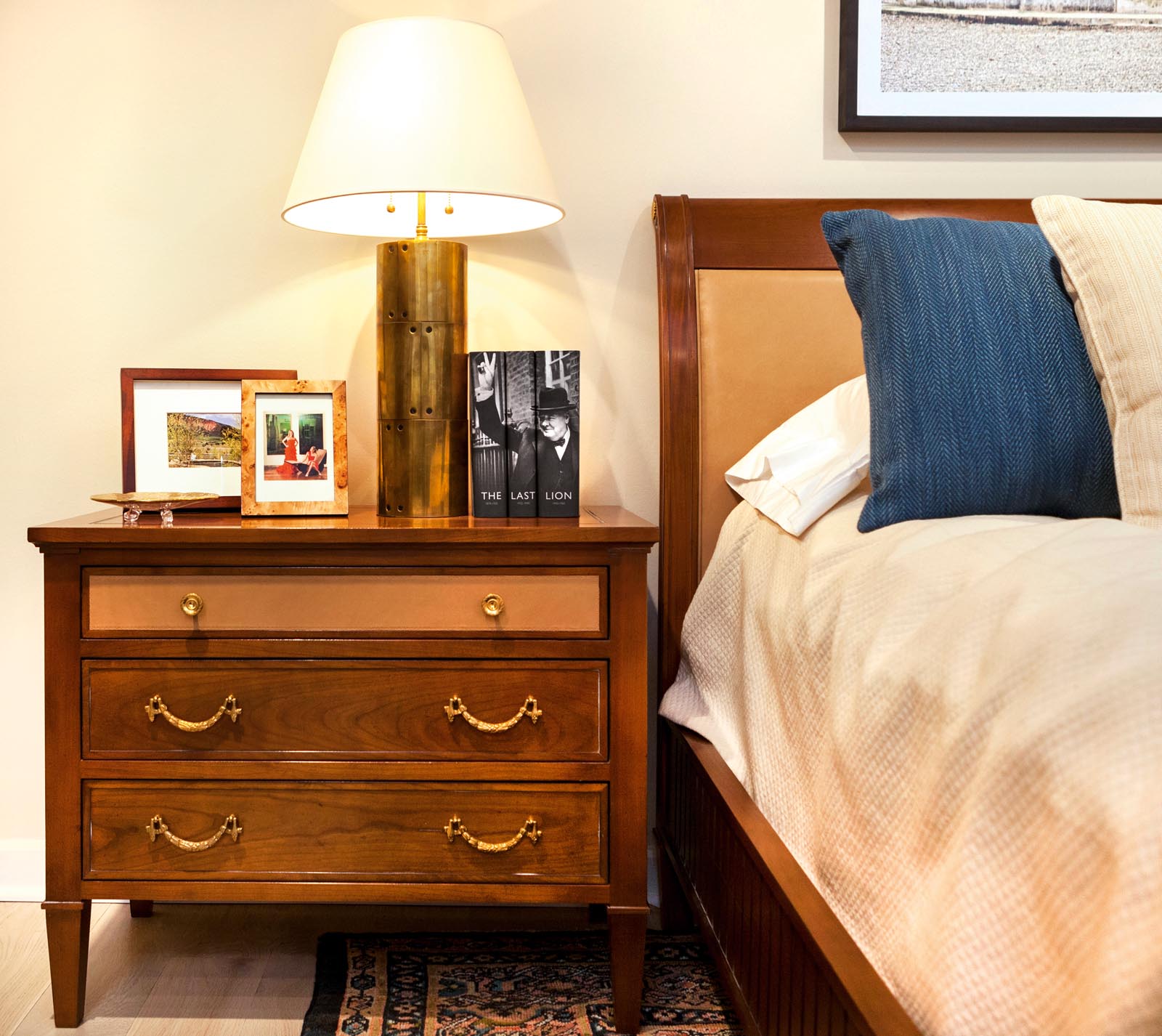 Photo of bedside drawers with framed photos and a group of custom-jacketed books.