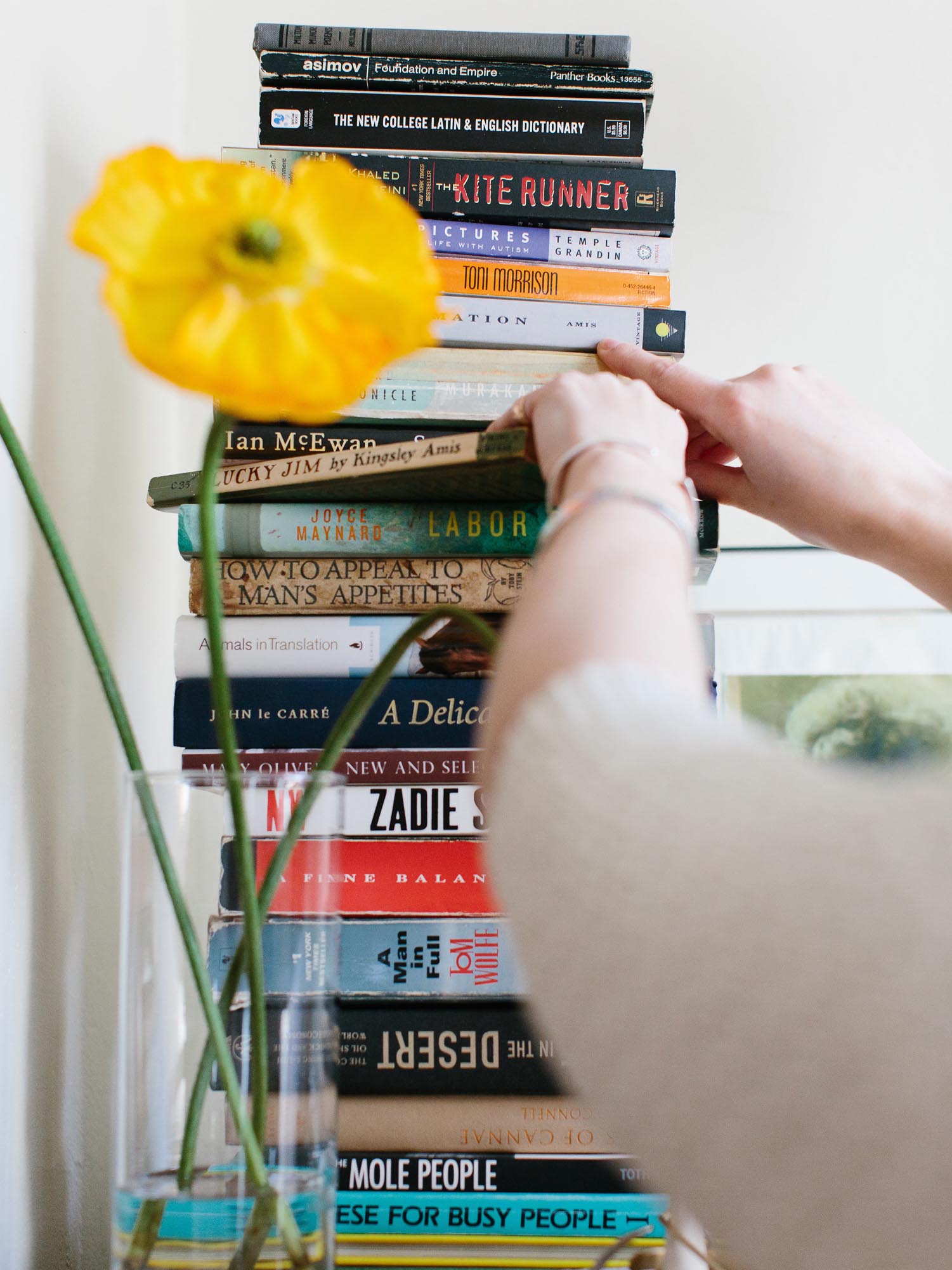 Photo of carefully removing a book from the middle of a tall stack.