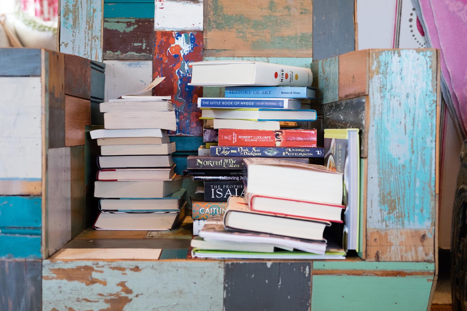 Photo of a niche made of scraps of wood holding stacks of books.