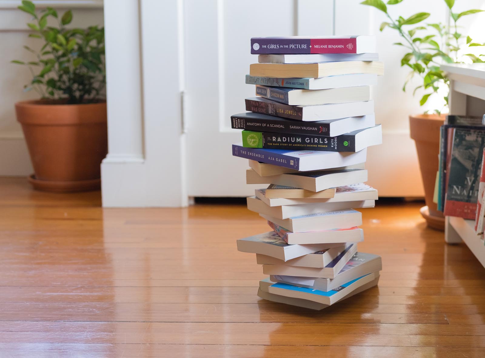 Photo of a stack of dozens of books on a polished floor.