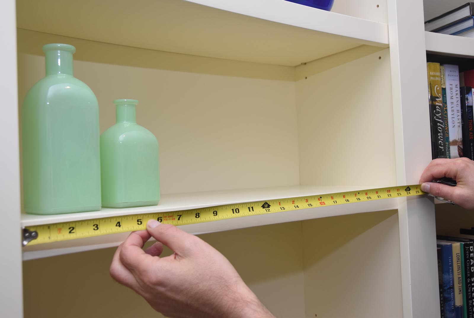 Photo of measuring the shelf, now containing a pair of bottles.