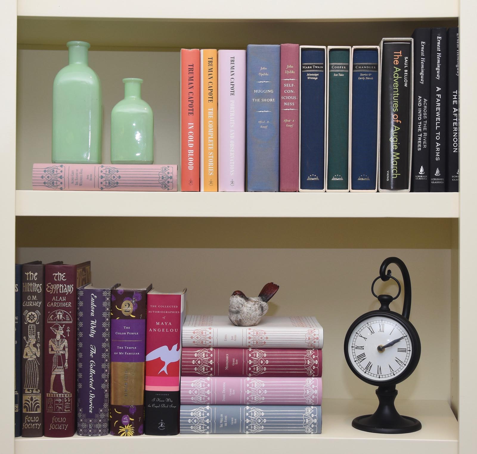 Photo of the pair of shelves, now styled, with custom jackets, horizontal stacks, and decorative objects.