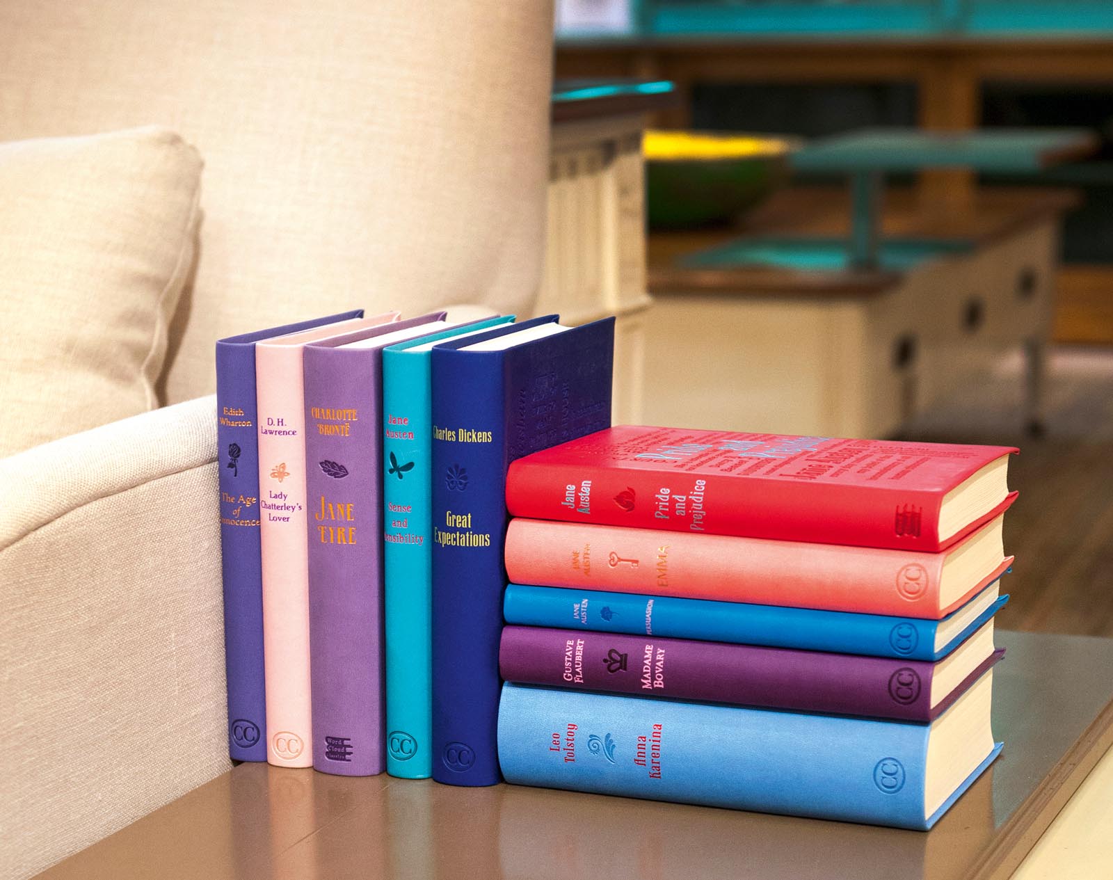 Photo of a colorful set of books arranged on a side table by a sofa.