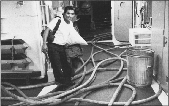 An unidentified sailor stands amid a tangle of fire hoses used to extinguish the blaze and to drain the ship. Courtesy Eric Sorensen