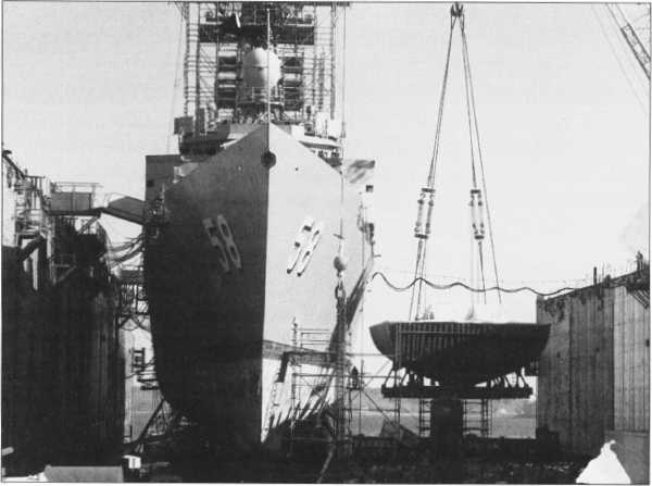 A crane lowers the Roberts’s 310-ton replacement engine room module into the dry dock at Bath Iron Works’ repair yard in Portland, Maine, ca. 1 December 1988.