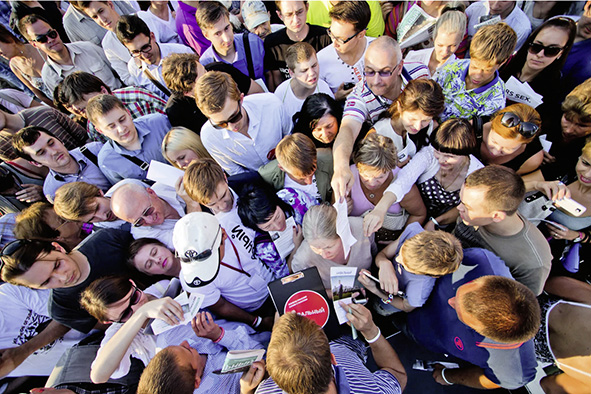 Alexej gibt Autogramme nach der Begegnung mit Wählern während des Bürgermeisterwahlkampfs 2013. Von oben fotografiert, sieht man eine Menge aus Köpfen und in der Mitte Alexej.