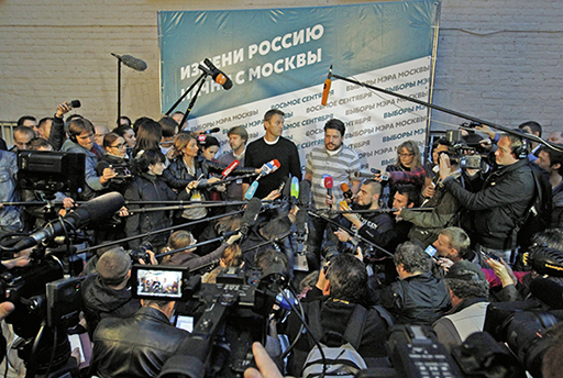 Wladimir Aschurkow, Alexej und Leonid Wolkow am Tag der Moskauer Bürgermeisterwahl 2013. Sie stehen auf einer Bühne, und zahllose Mikrophone und Kameras sind auf sie gerichtet.