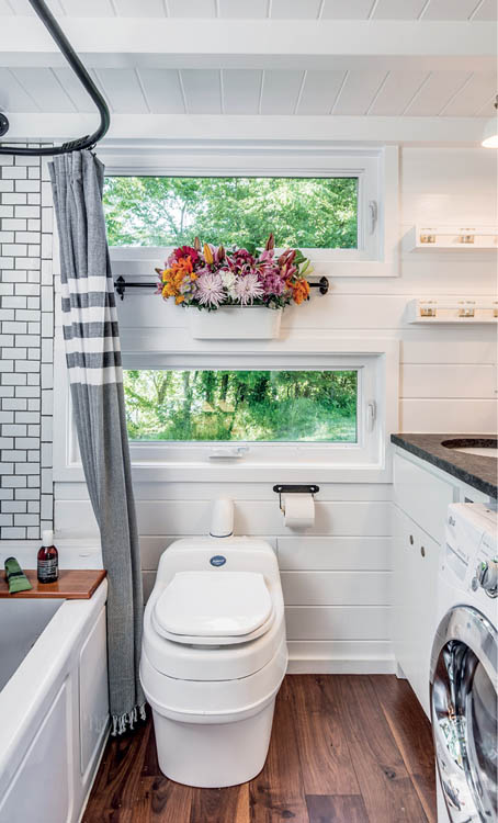 The bathroom of the Alpha Tiny House, with toilet, bathtub, and washer/dryer.