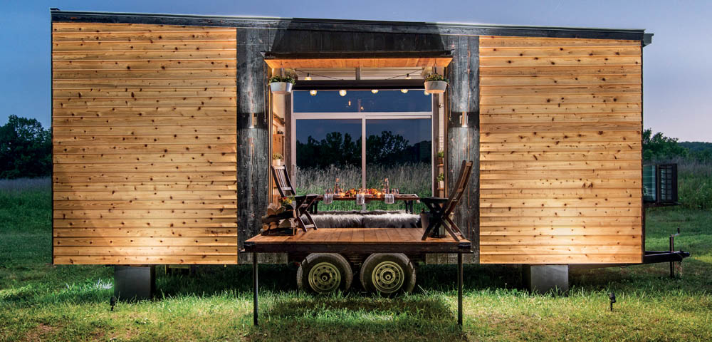 An exterior view of the Alpha Tiny House, lit up at sunset.