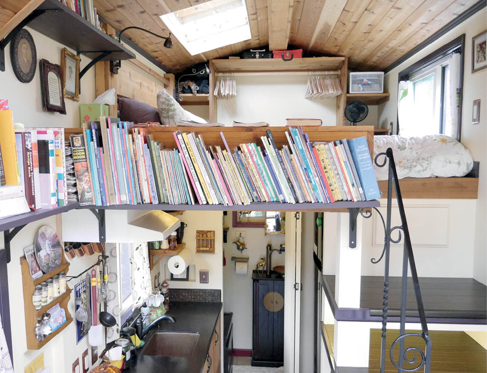 The interior of the Maiden Mansion tiny house, with a well-stocked book shelf.