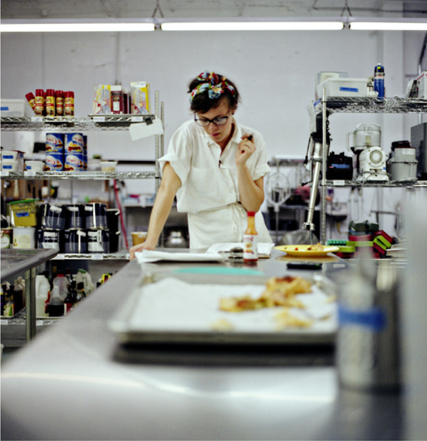 Thoughtfully looking down at a clipboard lying on a prep table, holding a pen