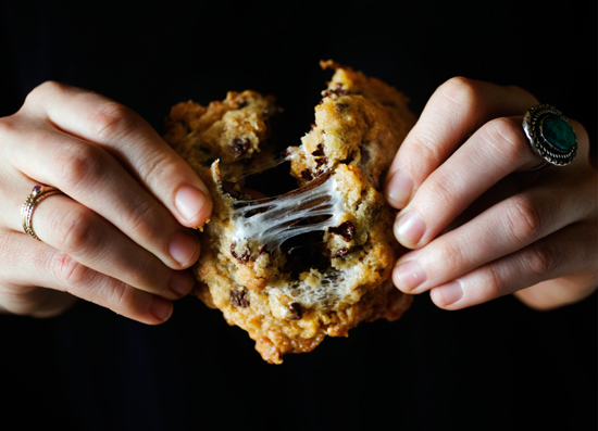 Hands breaking apart a cornflake-chocolate-chip-marshmallow cookie