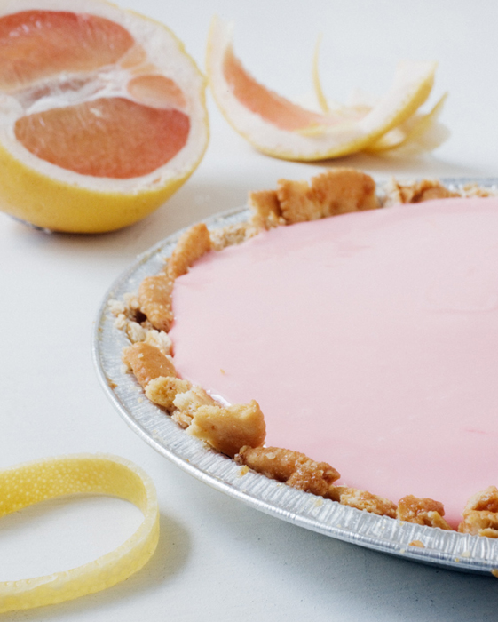 Grapefruit pie in a tin, grapefruits and peels in the background