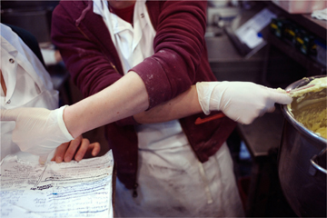 Mixing and pointing to a handwritten recipe held by another