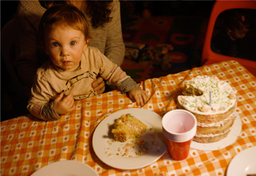 Child with cake on his face, the birthday cake on a white plate