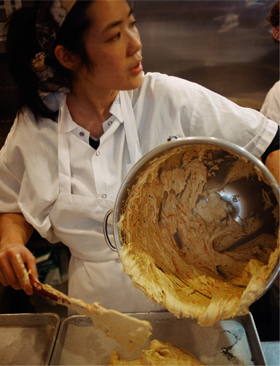 Pausing while scooping carrot cake mixture out of a large bowl