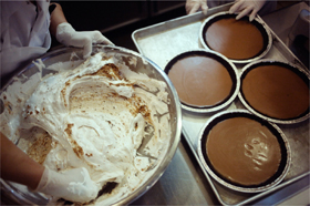 Mixing Peanut Butter Nougat in a large metal bowl, next to waiting pie crusts