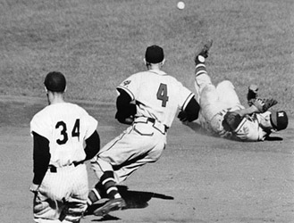 On an infield single by the Yankees’ Elston Howard, shortstop Johnny Logan tried to force out Tony Kubek (34) at second base with a toss to Red Schoendienst (4) during Game Two. (DAVID KLUG COLLECTION)