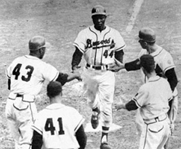 A Braves reception committee including Wes Covington (43), Eddie Mathews (41), and Johnny Logan (upper right) welcomed Henry Aaron (44) home after his three-run homer in the fourth inning gave Milwaukee an early lead. (DAVID KLUG COLLECTION)