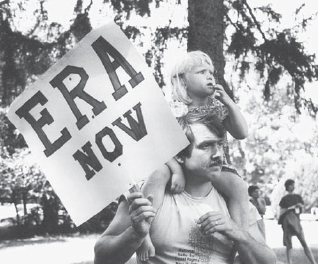 A young girl sits on her father’s...