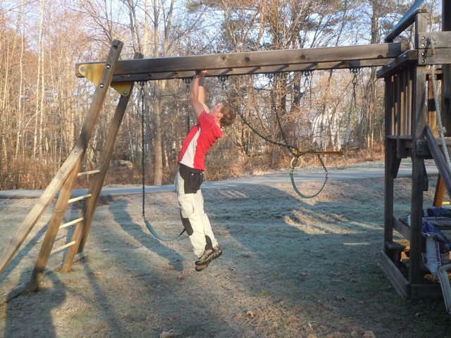 Palms in, a chin-up outdoors, with one foot hooked behind the other