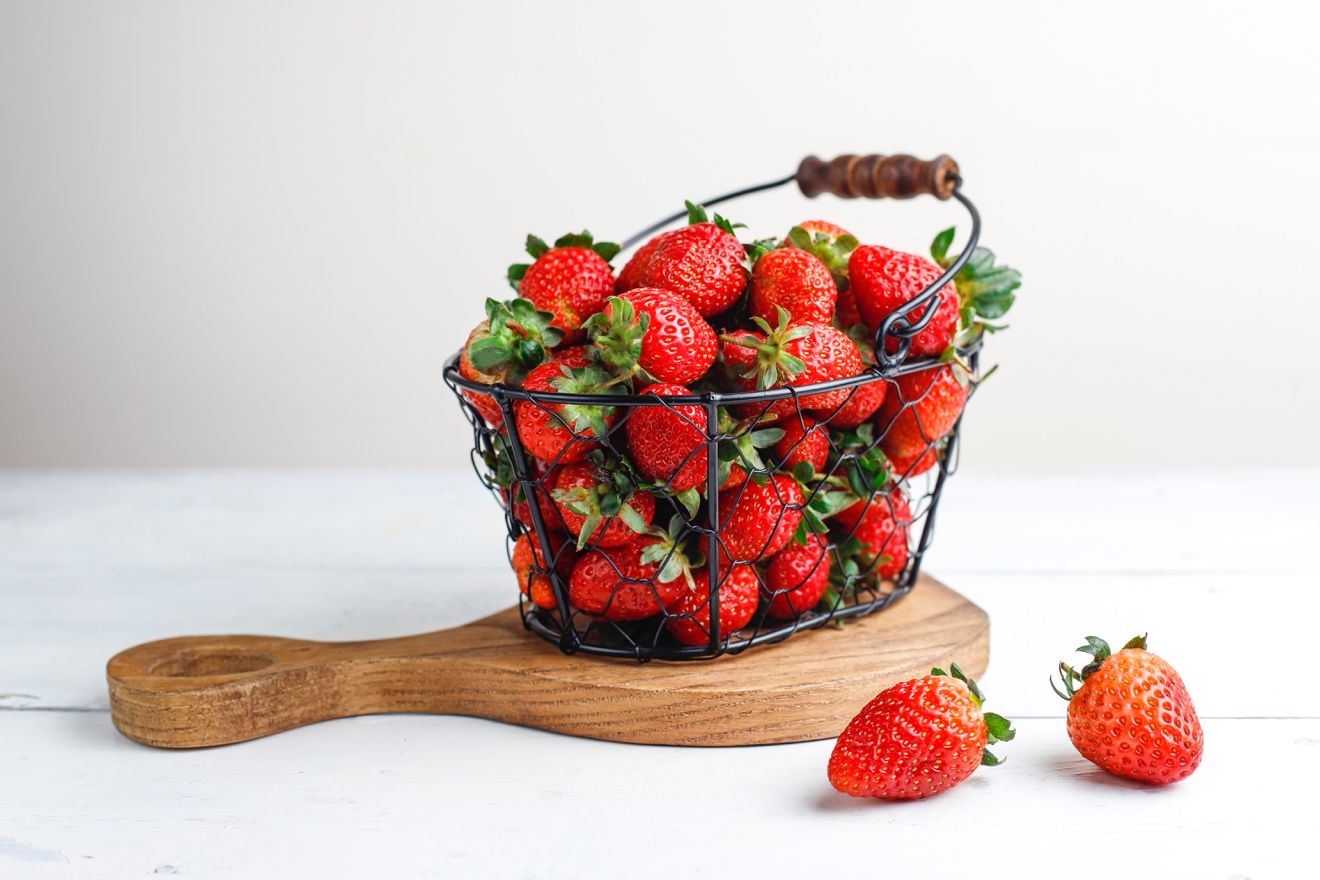 A bowl of fruit sitting on top of a wooden table  Description automatically generated