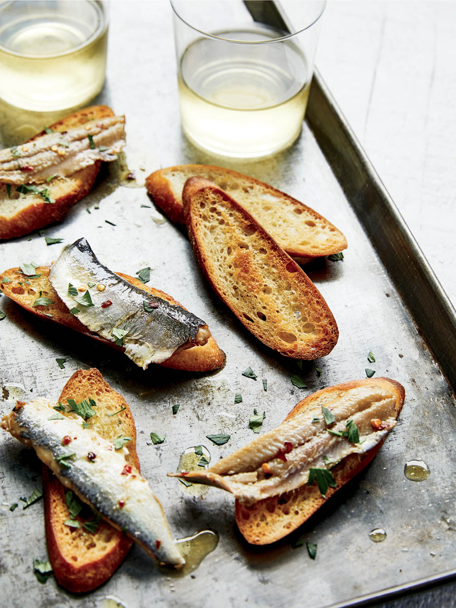 Cured anchovie fillets on toasted bread slices.