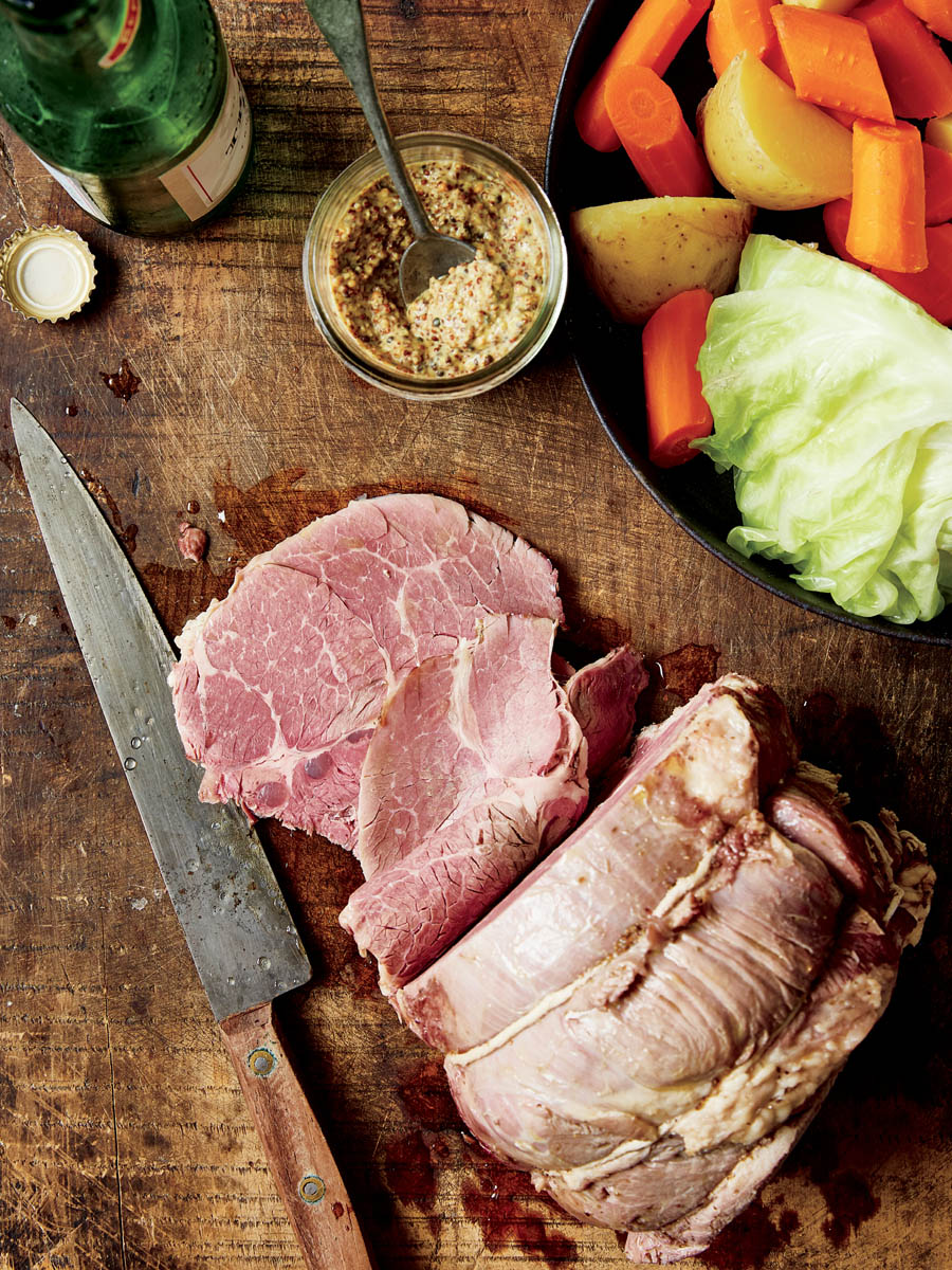 A spread of beef brisket with mustard, potato slices, salad, and carrots.