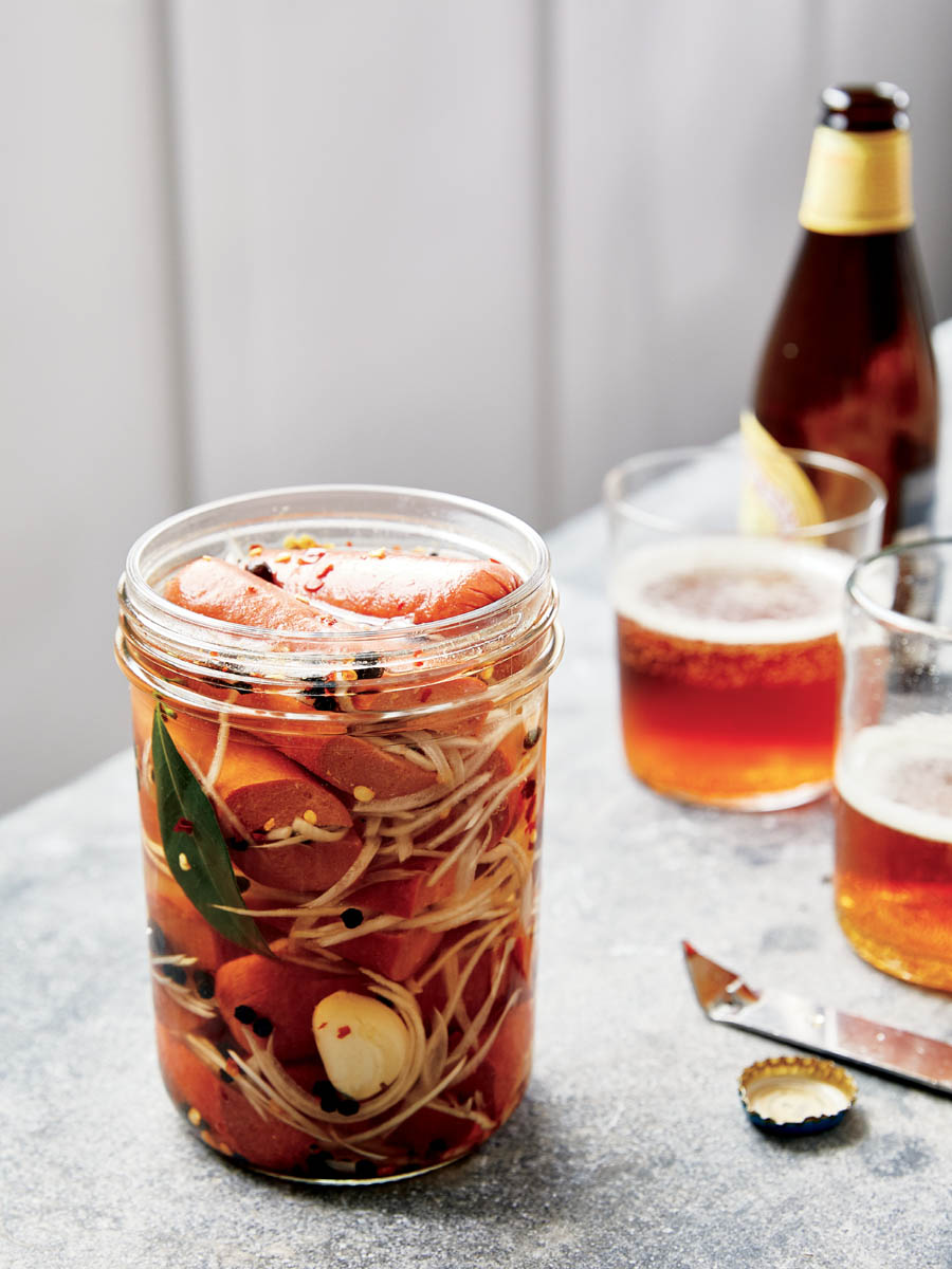 A jar of Czech pickled hot dogs with a bottle of beer.