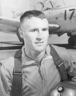 Ensign Jerry Grigsby’s official “after solo flight” photo at Saufley Field, Florida, in 1964. This training command publicity photo, like all others of its type, was taken in front of a picture of a T-34 trainer days before Grigsby’s first flight in Training Squadron 1. He is wearing newly issued flight gear and a fake parachute harness. The gold hard hat he’s holding is also a prop, as Navy flight helmets at the time were white. U.S. NAVY