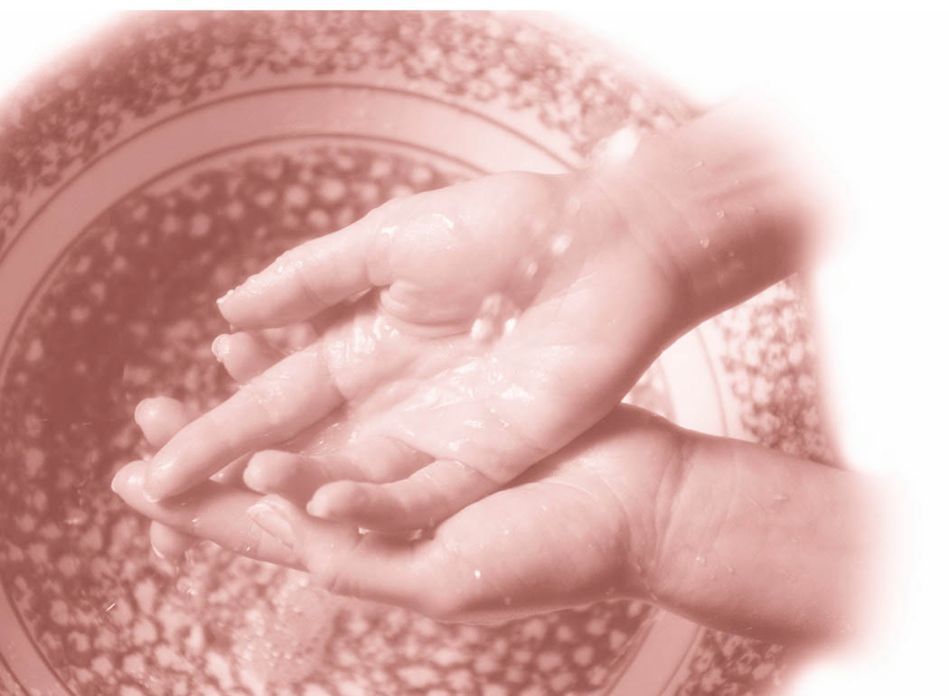 A woman washing her hands in a ceramic basin.