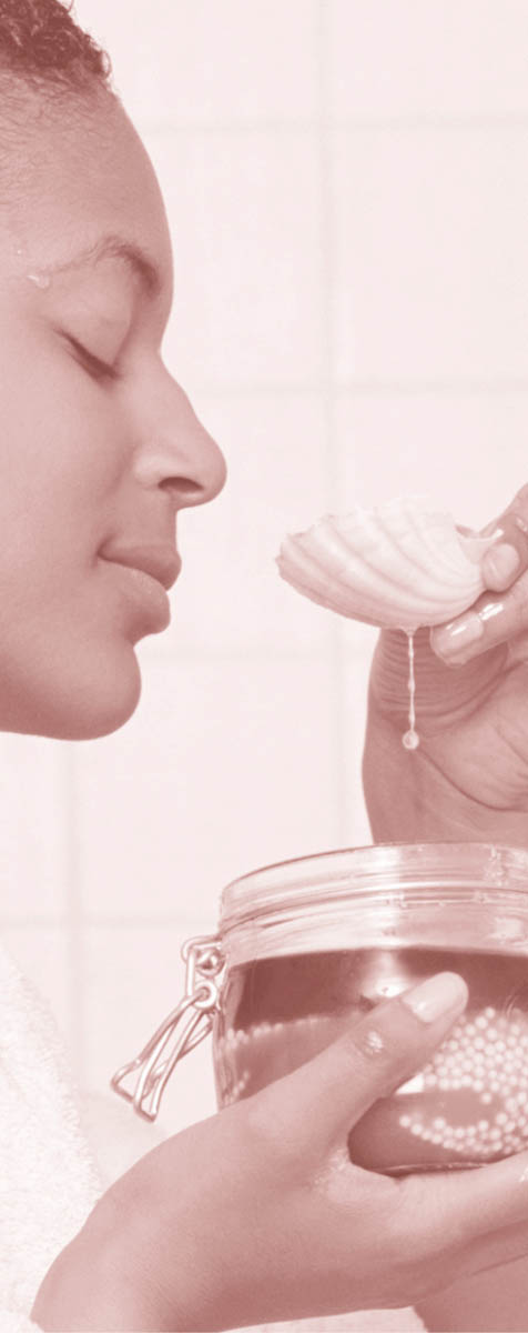 A woman smelling a spoonful of aromatic oils.