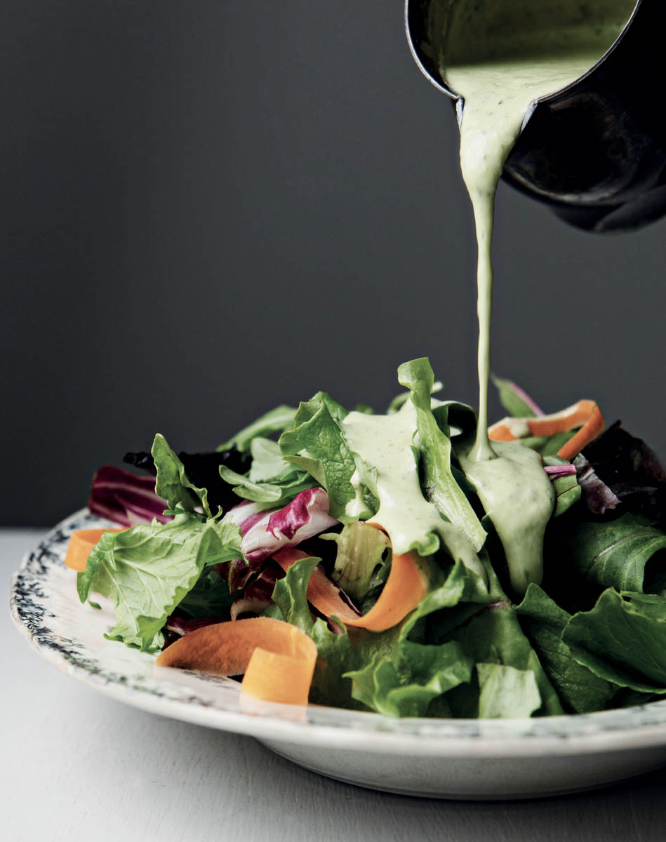 Pouring Greek goddess dressing onto a salad